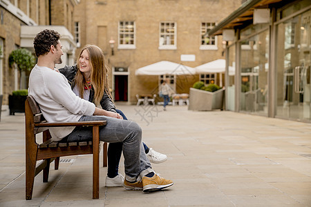 坐在英国伦敦KingsRoad国王路长椅聊天的年轻夫妇年轻女子高清图片素材