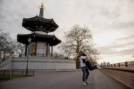 罗马青年男子在英国伦敦Battersea公园抱起女友，拥抱彼此，年轻夫妇高清图片素材