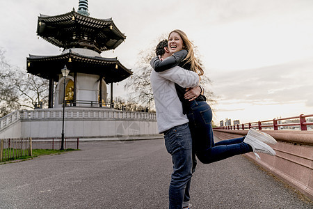 快乐的年轻人拥抱女友，英国伦敦巴特西公园，爱情，异性伴侣高清图片素材