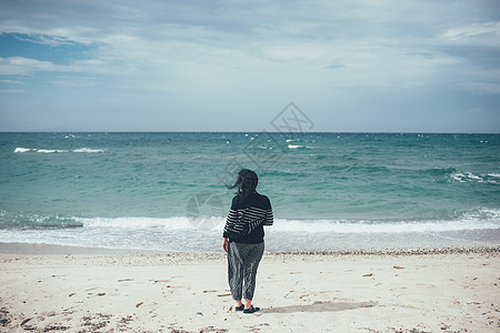意大利萨萨里索索海滩上看大海的女人的后视图图片