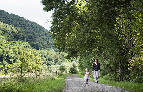 在德国北莱茵威斯特伐利亚州的农村公路上行走的母亲和女儿图片