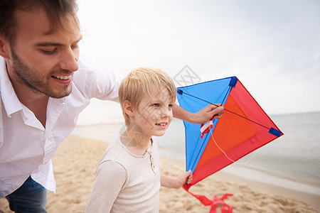 父亲和儿子在海滩玩风筝家庭高清图片素材