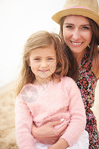 在海滩上看镜头的母亲和女儿家庭高清图片素材