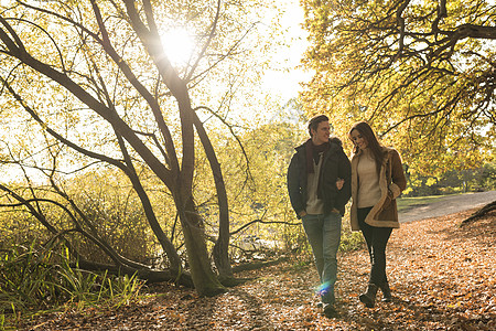 年轻夫妇在森林中行走手抱臂微笑图片