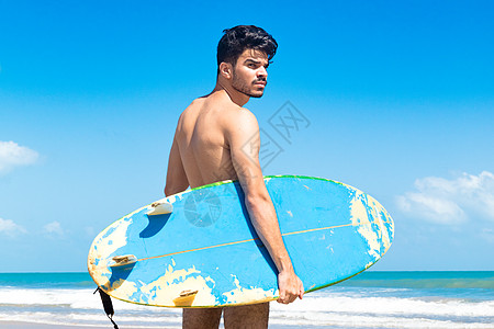 年轻人站在海滩上举着冲浪板巴西塞阿拉福塔莱萨背景图片
