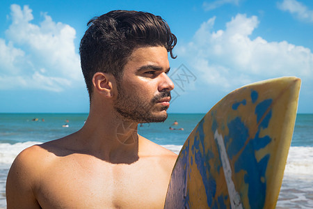 海滩上年轻男子持有冲浪板福塔莱萨巴西塞阿拉背景图片
