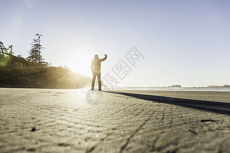 日出时海滩上的男人背影加拿大环太平洋公园图片