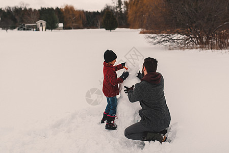 亲子活动父亲和女儿做雪人背景