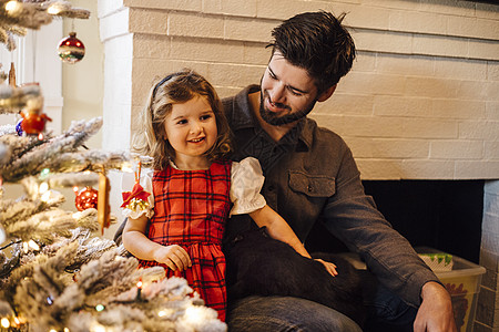 在圣诞树下与父亲坐在一起的女儿图片