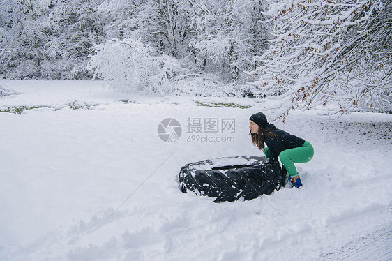 女人在雪中试图抬大轮胎图片