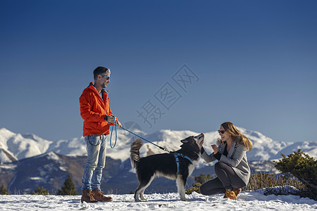 在雪中遛狗的情侣图片