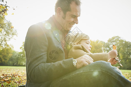 女儿坐在父亲的膝上抱着秋叶图片