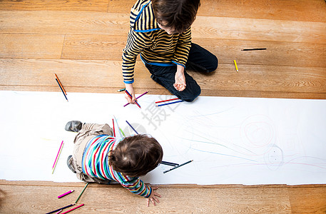 利用长纸对坐在地板上的男幼儿和大哥的俯视图片