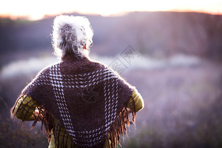 白头发老奶奶手叉腰看日落的背影图片