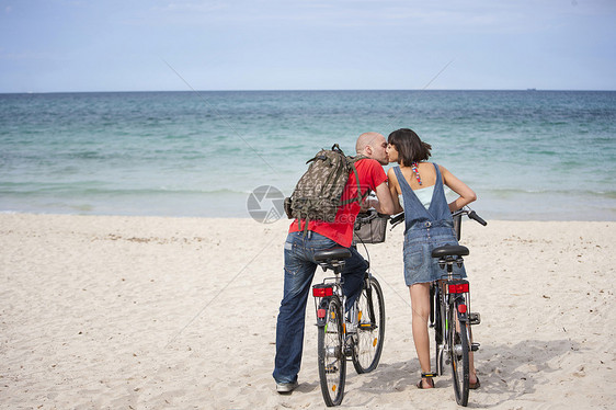 在西班牙马洛卡的海滩上骑自行车的夫妇图片