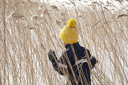 男孩走在雪地的长草丛里图片