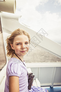 脖子上挂着望远镜的女孩在船上微笑图片