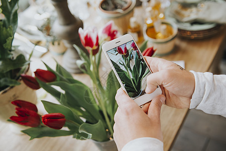 郁金香油画花店店员在用手机给花拍特写背景