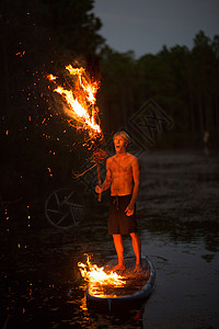 青年男子站在船桨板上举着火把图片
