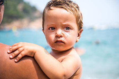 海滩被母亲抱着的男幼儿图片