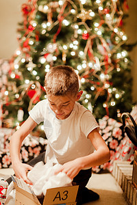 圣诞树前的男孩在拆礼物图片