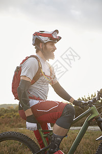 男子山地摩托车手在阳光普照的荒野上休息图片