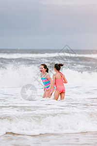 在美国阿拉巴马州道芬岛的海浪中站立着两个女孩图片