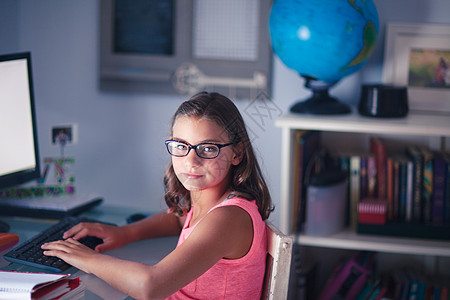 年轻女孩佩戴眼镜坐在办公桌使用计算机图片