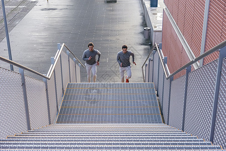 年轻男双胞胎一起在城市楼梯上跑步图片
