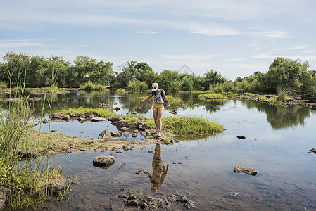 在瀑布附近探索平静水域的年轻女游客图片