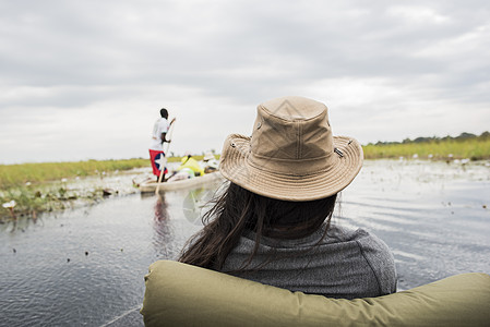 奥卡万戈三角洲看着男人划独木舟的女人博茨瓦纳非洲图片
