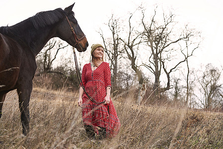 在野外牵着马带着笑容的女人肖像图片