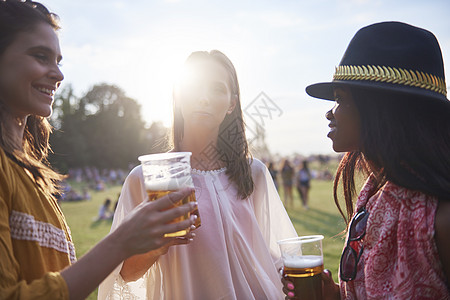 三个年轻的女朋友在霍利节带杯啤酒图片