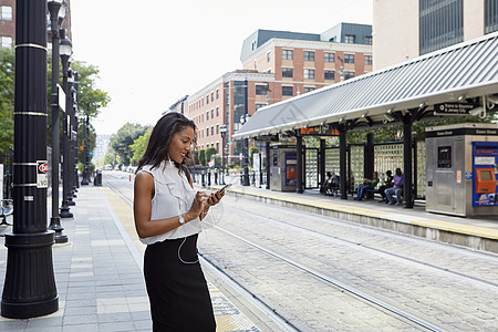 在轻型铁路站使用手机的女商人图片
