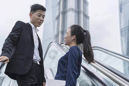 上海市在扶梯上说话的年轻男女商人图片