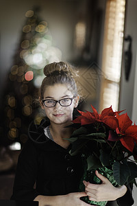 女孩在客厅里拿着圣诞植物盆栽图片
