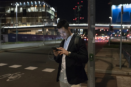 夜晚在街上的年轻商人看着手机意大利米兰图片