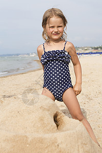 可爱女孩在沙滩上建堡穿着露天游泳服图片