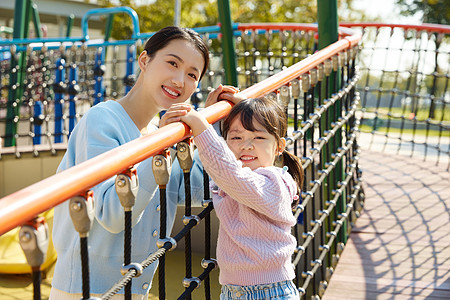 妈妈陪女儿在公园娱乐设施玩耍高清图片