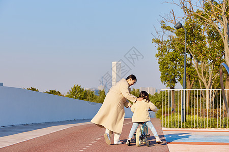 妈妈陪女儿在公园学习骑自行车图片