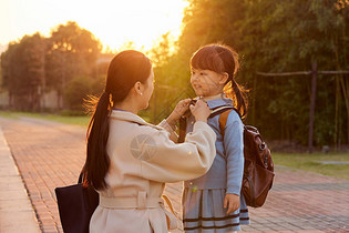 夕阳下妈妈为女儿整理衣服图片