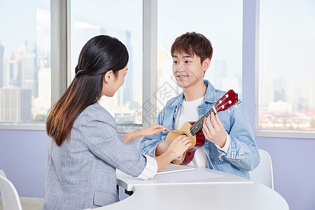 老师和大学生声乐教师教学生弹奏尤克里里背景