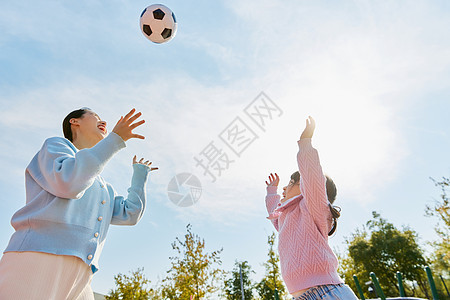 妈妈陪女儿户外玩耍踢足球背景图片