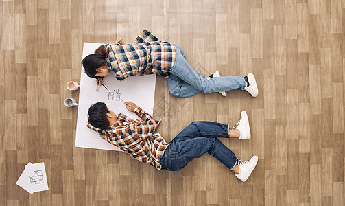 创意俯拍青年情侣趴在地板上绘图高清图片