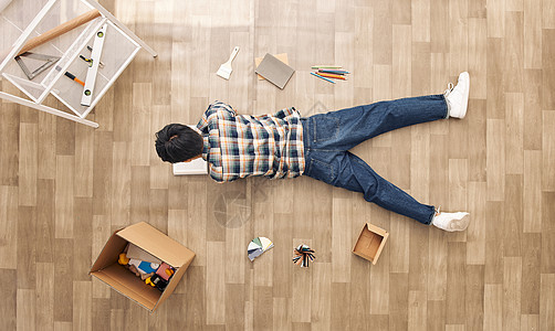 创意俯拍青年男性趴在凌乱的地板上看书图片