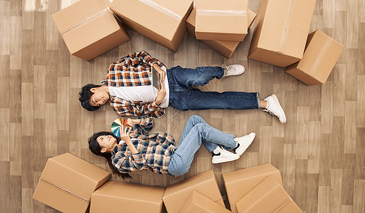 创意俯拍青年情侣躺在新家地板上看装修色卡图片