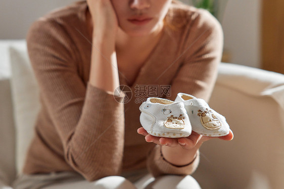 女性手捧着婴儿鞋特写图片