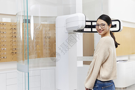 年轻女性站在验光机器前准备检查视力背景图片