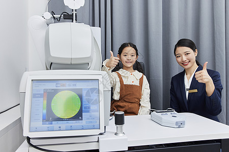 小女孩和验光师在验光机器前竖起大拇指高清图片