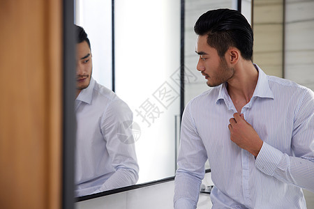 成熟男人对镜子整理仪表背景图片